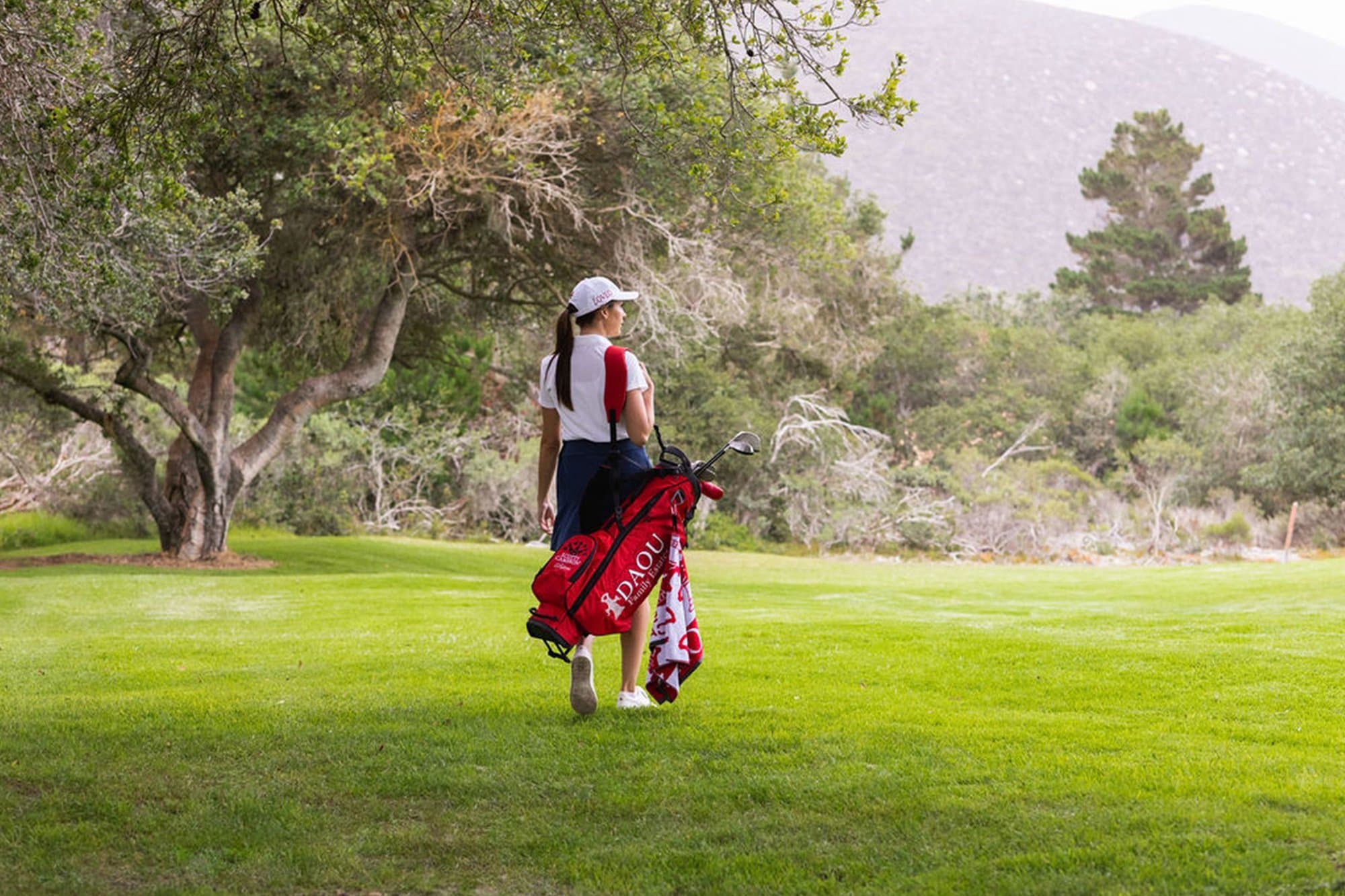 A golfer walking with the Scotty Cameron x DAOU golf bag